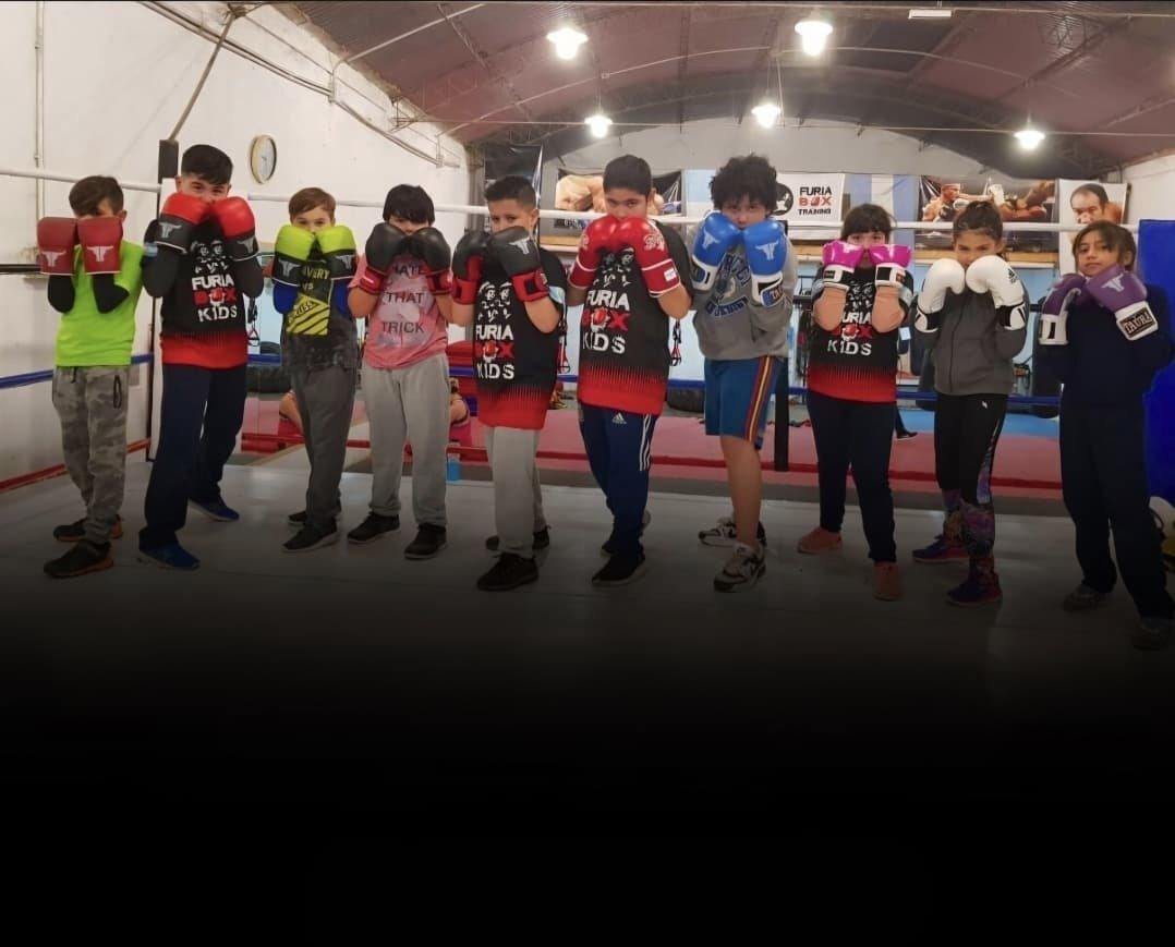 Grupo de niños y niñas con guantes en fila en el ring de furiabox Kids